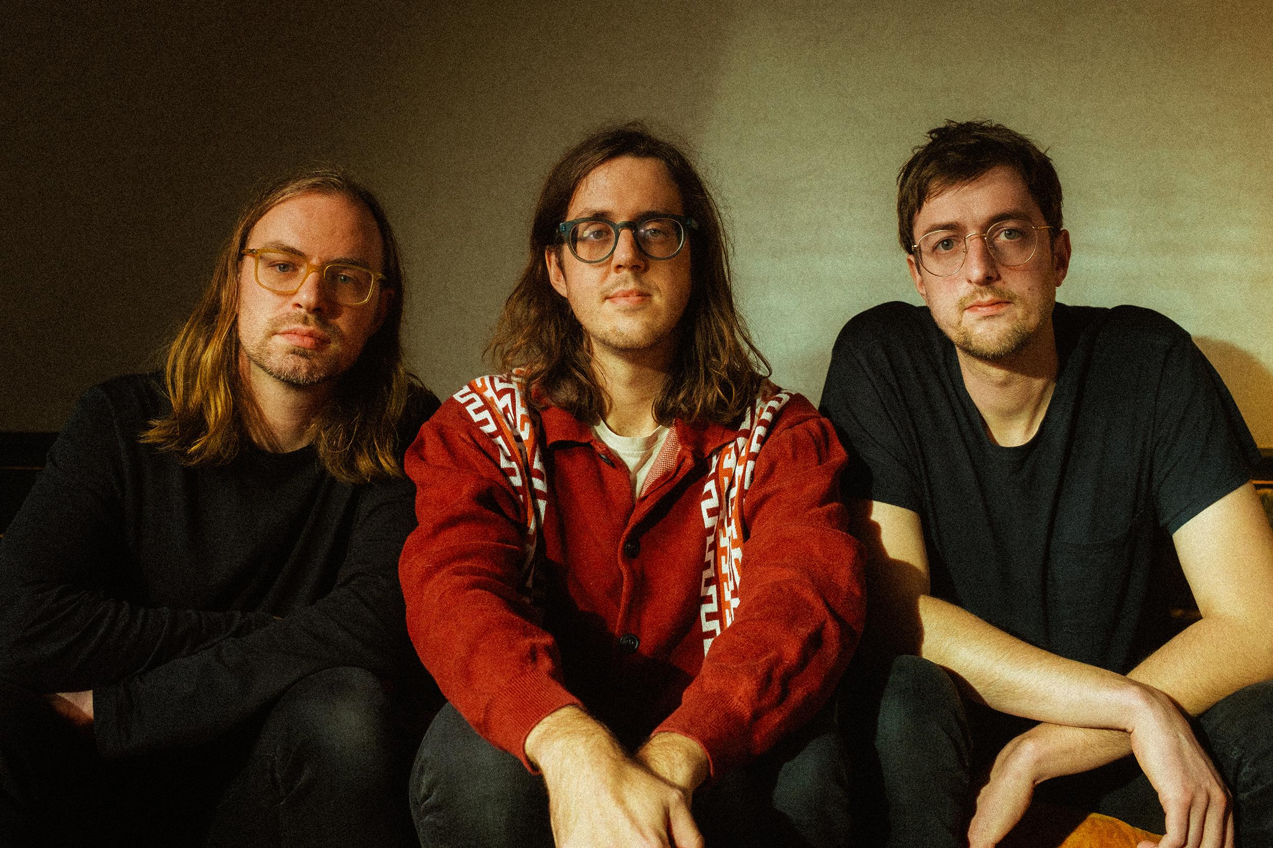 Tres integrantes de Cloud Nothings posan en una banca en una fotografía promocional.